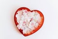 Colorful confetti in red heart shaped bowl on white background, flat lay. Happy Valentines day Royalty Free Stock Photo