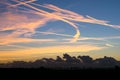 Contrails high up in the sky are colorful illuminated by the light of the setting sun