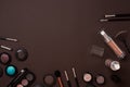 Colorful cosmetics on brown workplace with copy space. Cosmetics make up artist objects: lipstick, eye shadows, powder Royalty Free Stock Photo