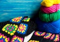 Colorful cotton grandmother's square against the background of multi-colored skeins in a wicker basket