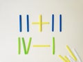 Colorful counting sticks for calculating mathematical operations for learning to count on light yellow background.