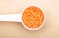 Red lentils on measuring spoon and brown background Royalty Free Stock Photo