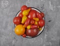 Variety of tomato cultivars in enamel bowl on concrete Royalty Free Stock Photo