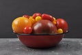 Variety of tomato cultivars in enamel bowl on concrete Royalty Free Stock Photo