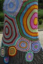 Colorful crochet knit on tree trunk in Kyiv, Ukraine. Street art goes by different names, graffiti knitting, yarn bombing. Royalty Free Stock Photo