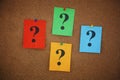 Colorful crumpled paper notes with question marks on them pinned to a cork board Royalty Free Stock Photo