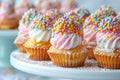 Colorful cupcakes with swirled pink and white frosting topped with generous amount of multi-colored sprinkles presented Royalty Free Stock Photo