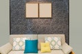 Colorful cushion pillows on modern beige color fabric sofa  with wooden picture frames on the grey brick wall interior for office Royalty Free Stock Photo