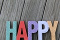 Colorful cut-out words that read 'happy' on wood background