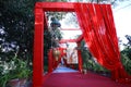 Colorful decorated outdoor entrance gate at wedding scene with red curtains and chandelier, park or lawn background,