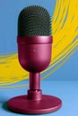 A colorful design microphone against a sky blue wall painted with yellow brushstrokes. Royalty Free Stock Photo