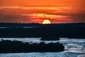 Colorful and detailed sunset with orange sky, blue water and birds