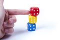 Colorful dice tower being pushed and knocked down by a humans hand / finger, a tall structure of game dice about to fall over