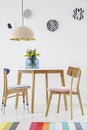 Colorful dining room interior with a table, chairs, striped rug, pastel chandelier and hanging plates on the wall Royalty Free Stock Photo