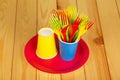 Colorful disposable tableware: glasses, plates and forks on light wood. Royalty Free Stock Photo