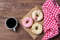 Colourful donuts on baking paper and cup of coffee, wooden background, top view Royalty Free Stock Photo