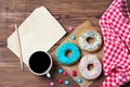 Colourful donuts, cup of coffee, smarties and old blank paper sheet with pencil on wooden table, top view Royalty Free Stock Photo