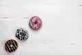 Colorful donuts on white wooden table. Sweet icing sugar food with glazed sprinkles, doughnut with frosting. Top view with copy Royalty Free Stock Photo