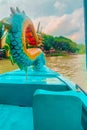 A colorful dragon head decorates the front of a blue boat on a river, with lush greenery in the background. Royalty Free Stock Photo
