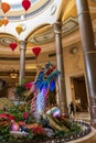 A colorful dragon sculpture surrounded by large gold coin, colorful flowers and lush green plants at The Venetian Resort and Hotel