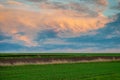 Colorful dramatic sky at sunset. Field with green shoots of agricultural plants and plowed land Royalty Free Stock Photo