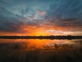 Colorful and dramatic sunset sky reflecting on pond water. Silent evening scene at Delia lake. Vibrant sundown clouds at the Royalty Free Stock Photo