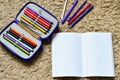 Colorful drawing pencils and open epmty notebook