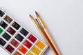 Colorful dry watercolor tablet set and white plastic palette and paint brushes and pencils on white texture background Royalty Free Stock Photo