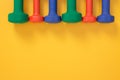 Colorful dumbbells on joyful yellow background