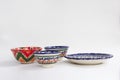 Colorful east ceramic plates and bowls with national pattern in blue and red colors on white background, Tashkent,