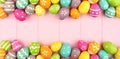 Colorful Easter banner with a double border of Easter Eggs over a pink wood background with copy space Royalty Free Stock Photo