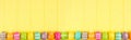 Colorful Easter banner with a row border of Easter Eggs over a yellow wood background with copy space Royalty Free Stock Photo