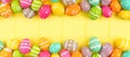 Colorful Easter banner with double border of Easter Eggs over a yellow wood background with copy space Royalty Free Stock Photo