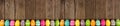 Colorful Easter banner with row border of Easter Eggs over a dark wood background with copy space Royalty Free Stock Photo