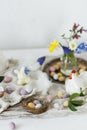 Colorful easter chocolate eggs in nest, spring flowers, chicken figurine and linen cloth on rustic wooden table. Space for text. Royalty Free Stock Photo