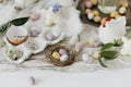 Colorful easter chocolate eggs in nest, spring flowers, chicken figurine and linen cloth on rustic wooden table. Space for text. Royalty Free Stock Photo