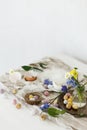 Colorful easter chocolate eggs in nest, spring flowers, feathers and linen cloth on rustic wooden table. Space for text. Easter Royalty Free Stock Photo