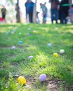 Colorful Easter egg on green grass meadow with blurry long line of diverse kids parents waiting for egg hunt tradition Royalty Free Stock Photo