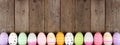 Colorful Easter Egg long bottom border over a rustic wood banner background Royalty Free Stock Photo