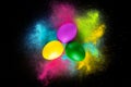 Colorful Easter eggs on the background of a mixture of colors. Colorful powder on black background. Royalty Free Stock Photo