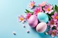 Colorful Easter eggs and blooming pink flowers on light blue background. Royalty Free Stock Photo