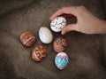 Colorful Easter eggs on burlap, female hand chose and pick one Royalty Free Stock Photo