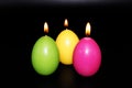 Colorful Easter eggs candles exposed on black background