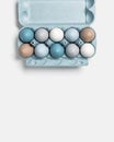 Colorful Easter eggs in carton packing, blue, beige, white neutral colors, festive chicken egg in paper container on