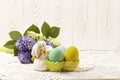 Colorful Easter eggs in a ceramic rabbit stand and a spring bouquet with lilac and yellow flowers on a beautiful knitted napkin on Royalty Free Stock Photo