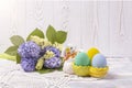 Colorful Easter eggs in a ceramic rabbit stand and a spring bouquet with lilac and yellow flowers on a beautiful knitted napkin on Royalty Free Stock Photo