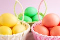 Colorful Easter eggs in colored baskets. Pink background. Easter holiday concept