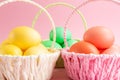 Colorful Easter eggs in colored baskets. Pink background. Easter holiday concept