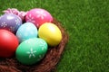 Colorful Easter eggs in decorative nest on grass, closeup. Space for text Royalty Free Stock Photo