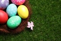 Colorful Easter eggs in decorative nest on grass, closeup. Space for text Royalty Free Stock Photo
